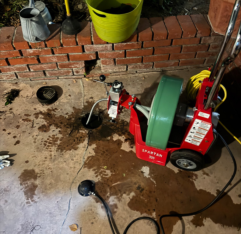 Drain cleaning machine operating on a wet garage floor with water and debris